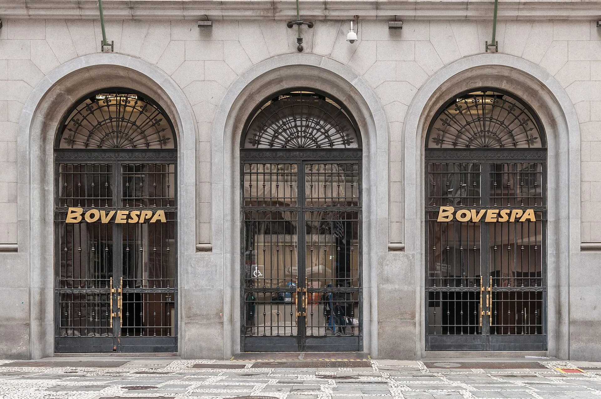 Fachada de pedra com três entradas em arco, portas de ferro preto e o nome BOVESPA em letras douradas, no centro de São Paulo