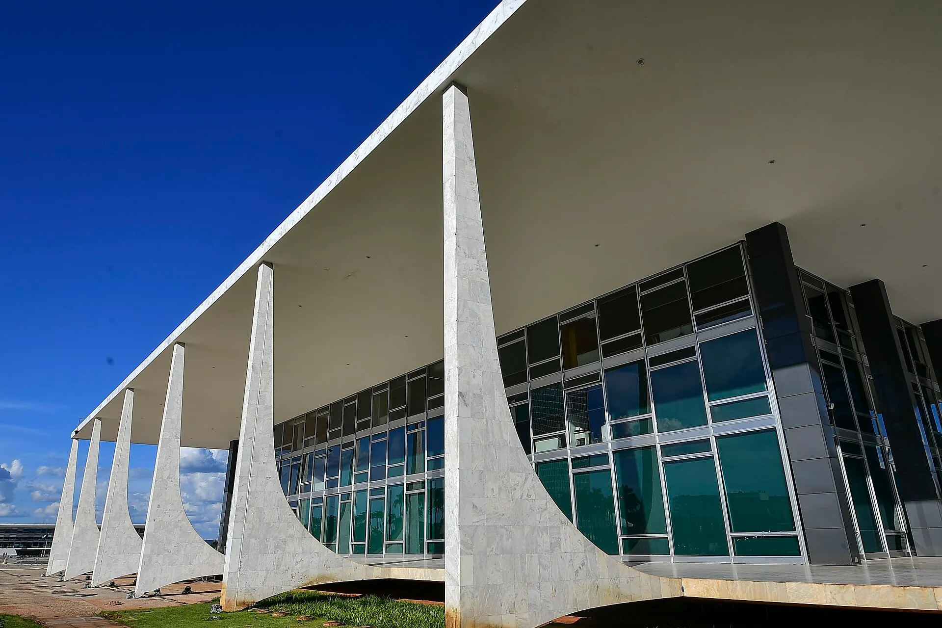 Fachada do Supremo Tribunal Federal, em Brasília, com colunas de mármore, grandes vidraças e céu azul