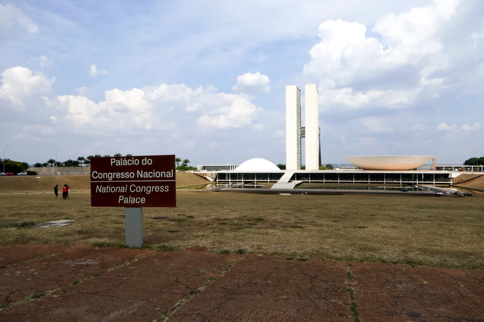 Fachada do Congresso Nacional, em Brasília, com as duas torres e as cúpulas da Câmara e do Senado, ao lado de uma placa com o nome do prédio